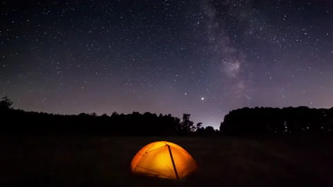 Orange iluminated tent in the forest under the starry sky. Timelapse Video stock 141172272