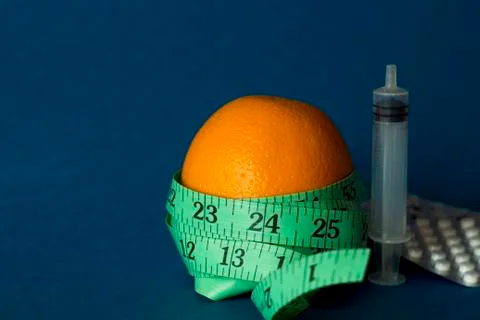 Orange with an inch lying on blue background Stock Photos