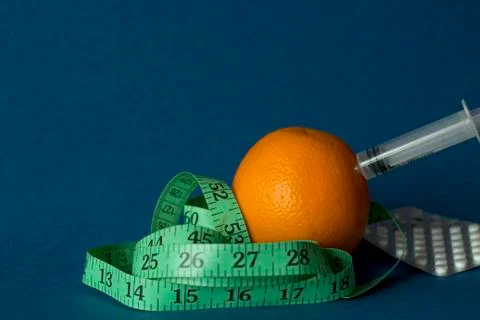 Orange with an inch lying on blue background Stock Photos