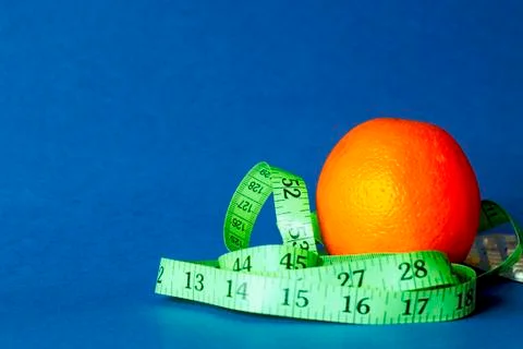 Orange with an inch lying on blue background Stock Photos