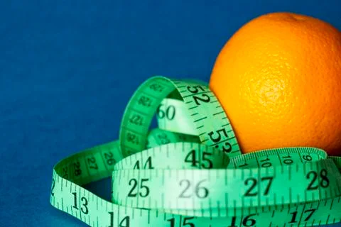 Orange with an inch lying on blue background Stock Photos