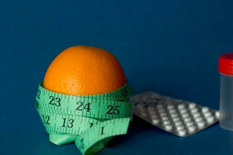 Orange with an inch lying on blue background Stock Photos