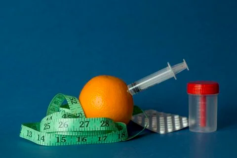 Orange with an inch lying on blue background Stock Photos