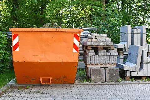 Orange industrial transportable dumpster container and cobble stones on palette Stock Photos