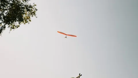 Orange isolated hang glider flying against grey cloudy sky. Hang-glider flying Video stock 117444075