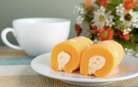 Orange jam rolls on white a dish with a cup of coffee Stock Photos