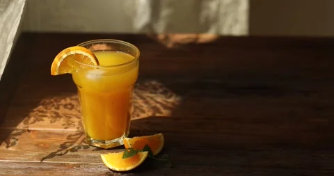 Orange juice in a glass on the table by the window. Glare from the sun Stock Footage 246001904