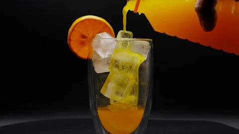 Orange juice pouring into ice cube glass rotated. Vídeo Stock 250144806