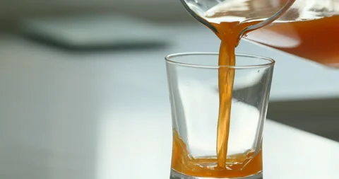 Orange juice is pured from a jug into a glass Stock Footage 154802553