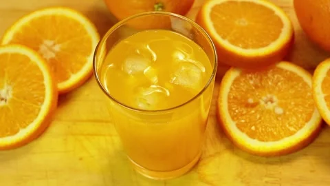 Orange juice served with ice cubes and surrounded by fresh citrus fruits an.. Stock Footage 338337151