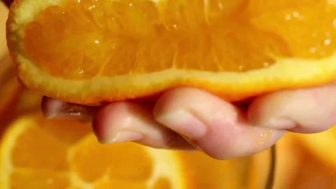 Orange juice splashes from half of fruit in hand, close up of squeezing orange Video stock 336588941
