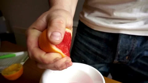 Orange juice splashes from half of fruit in hand, close up of squeezing orange Stock-Footage 336588956