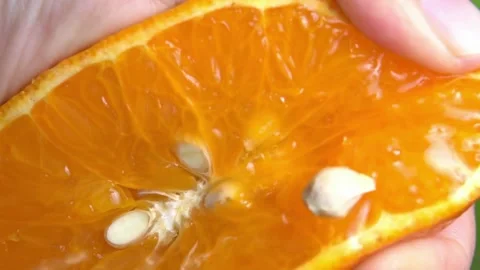 Orange juice splashes from half of fruit in hand, close up of squeezing orange Stock-Footage 336588978