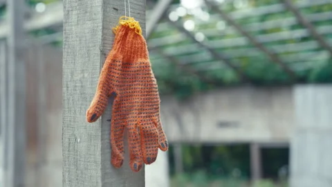 Orange Knitted Work Glove Hanging on Wooden Post at Construction Site Stock Footage 336516997