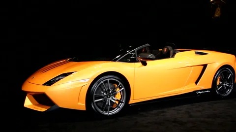 Orange Lamborghini in front of black curtains at the auto show Stock Footage 1094194