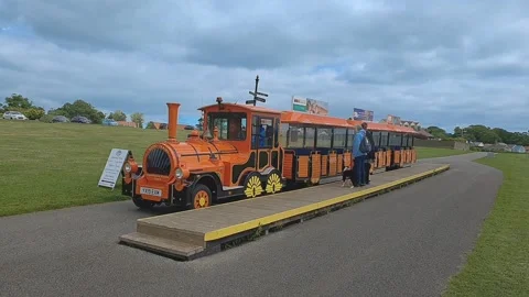Orange land train pulling into and stopping at the platform Stockbeeldmateriaal 202937093