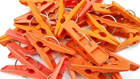 Orange laundry clips rotating on the white background, plastic clothes pins.. Stock Footage 306201117