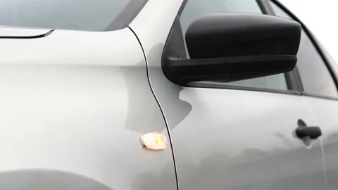 Orange left front turn signal light on silver car or emergency flashing car Stock Footage 165871574