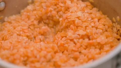 Orange lentils are cooked close-up, parallax. Cooking process by heat treatment Stock Footage 231210094