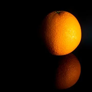 Orange lies on the table on a black background, fruit Stock Photos