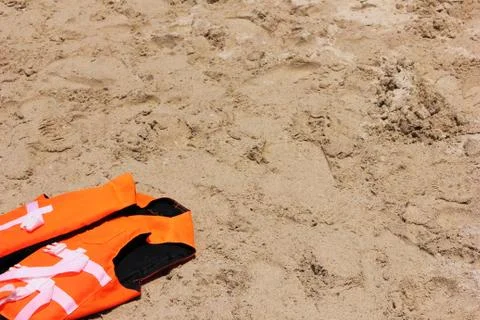 Orange life jacket lying on the sand. Safety on the water. Stock-Fotos