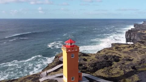 Orange lighthouse over tough cliffs in Iceland Stock Footage 168257687