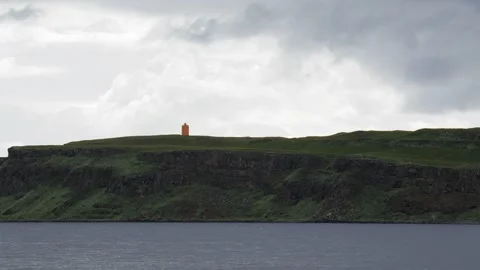 Orange Lighthouse Standing on a Green Cliffside in Iceland Stock Footage 339790745