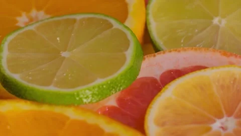 Orange, lime, grapefruit and lemon fruit slices on rotating surface - close up Stock Footage 340430567