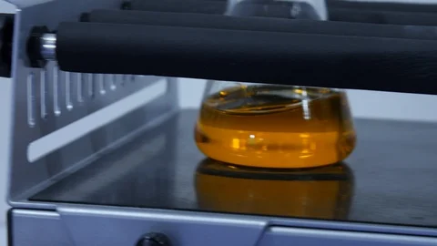 Orange liquid is mixed by a machine in a laboratory Stock Footage 126715785