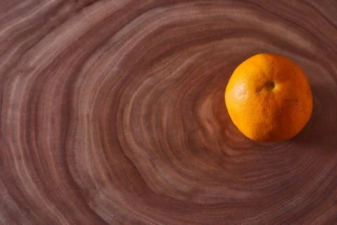 A orange mandarin lies on a slice of a tree. Wooden background Stock Photos