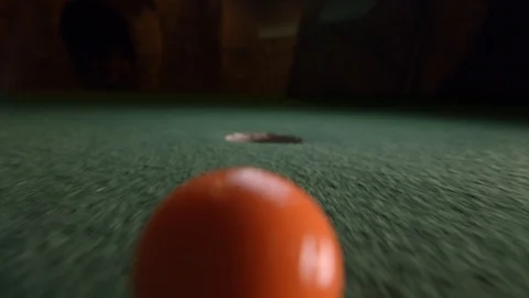 An orange mini golf ball falls into the golf hole and bounces in the Stock Footage 104379568