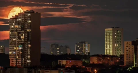 Orange moon setting behind city skyscrapers and clouds time lapse Stock Footage 340549567