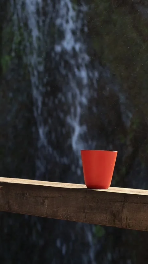 Orange mug against the background of a waterfall, outdoor, vertical Stock Footage 290165311