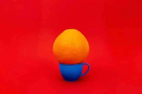 Orange at mug on red background Stock Photos