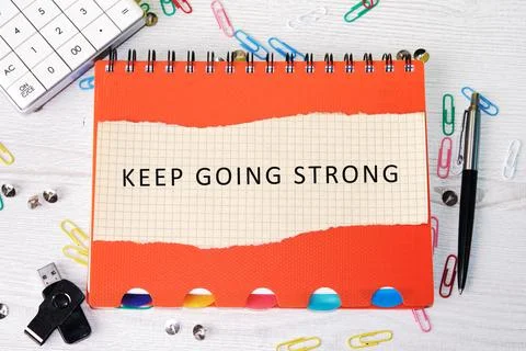 An orange notebook with the inspiring words KEEP GOING STRONG sits open Stock Photos