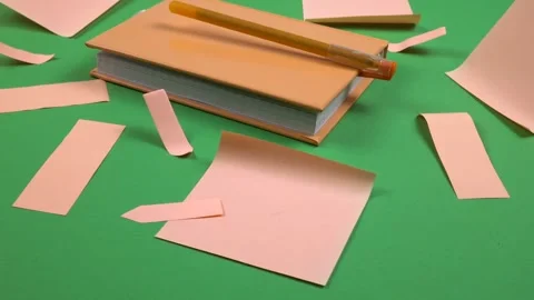 Orange notepad, sticky notes and ballpoint pen lie on a green background Stock Footage 336507406