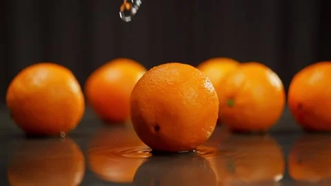 An orange orange rotates in slow motion on a dark wet surface. Stock Footage 271264006