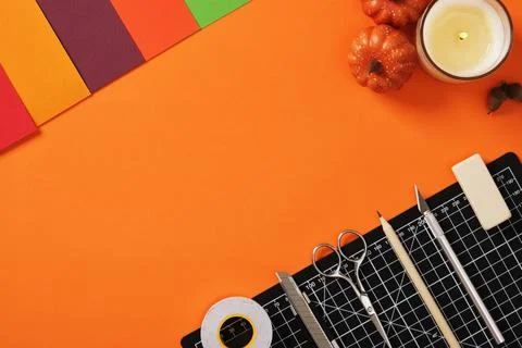 Orange paper crafting work table. Colorful paper and tools: scissors, knives, Stock Photos
