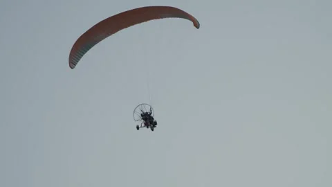 An orange paraglider is flying in the sky Stock Footage 329552151