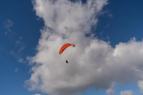 Orange paraglider in the sky in the clouds Stock Photos
