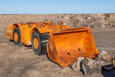An orange payloader for low clearance underground mining stands retired. 库存照片