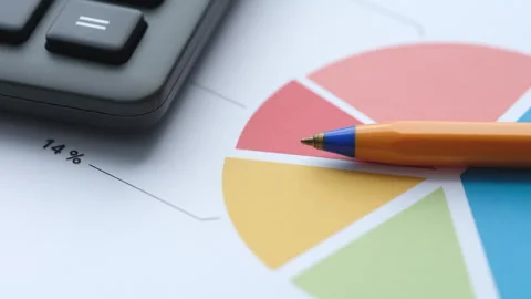 An orange pen lying on a colorful pie chart document Stock Footage 337262161