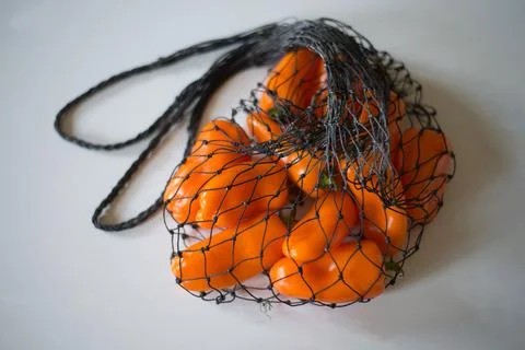 Orange pepper in a mesh natural string bag. Stock Photos