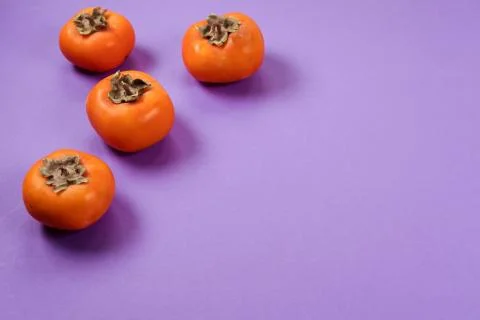 Orange persimmons on violet background. Copy space. Healthy food, fresh fruits Stock Photos