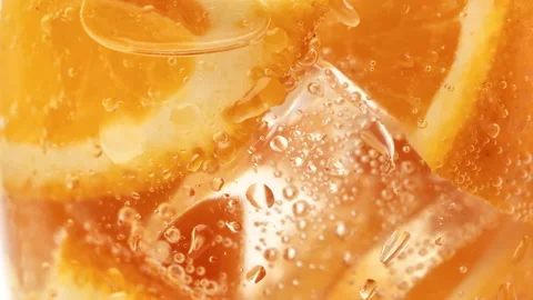 Orange pieces with ice cubes and fizzy carbonated water bubbles in glass summer Stock Footage 179069037