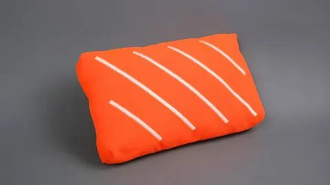 Orange pillow with white stripe pattern on gray background Stock Photos