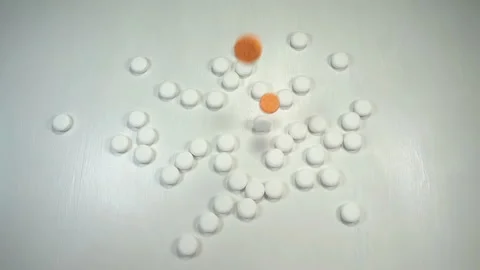 Orange pills falling in slow motion on white pills Video stock 140758594