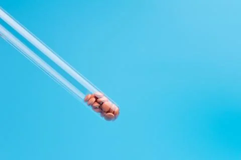 Orange pills or tablets drop out of the test tube on blue background Stock Photos
