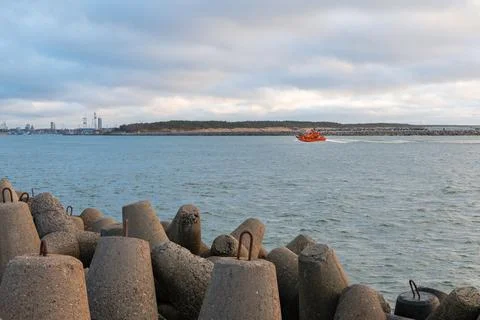 Orange Pilot Boat Navigating Through Harbor Entrance with Breakwater Stock Photos