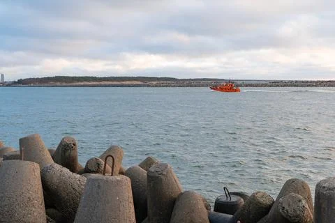 Orange Pilot Boat Navigating Through Harbor Entrance with Breakwater Stock Photos